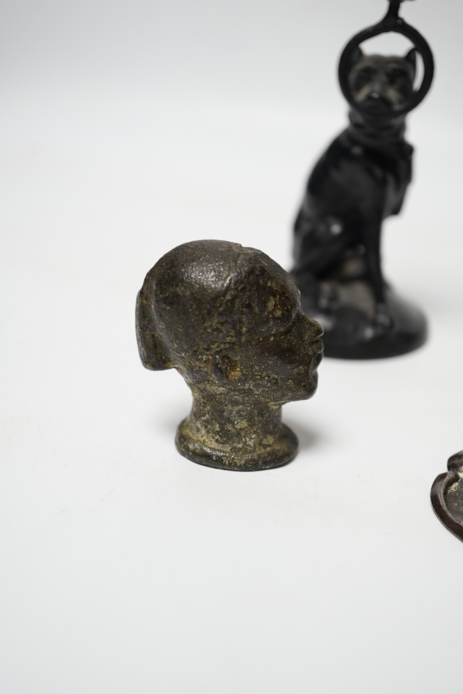 A Victorian brass hand paper clip, a small bronze tribal head and novelty dog candlestick, tallest 15cm high